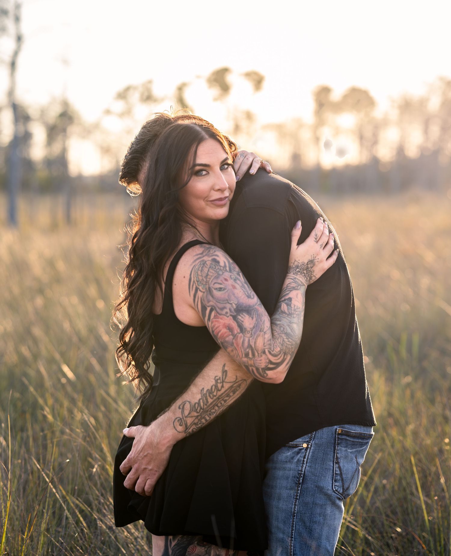 Romantic outdoor photoshoot featuring couple in natural grassland setting.