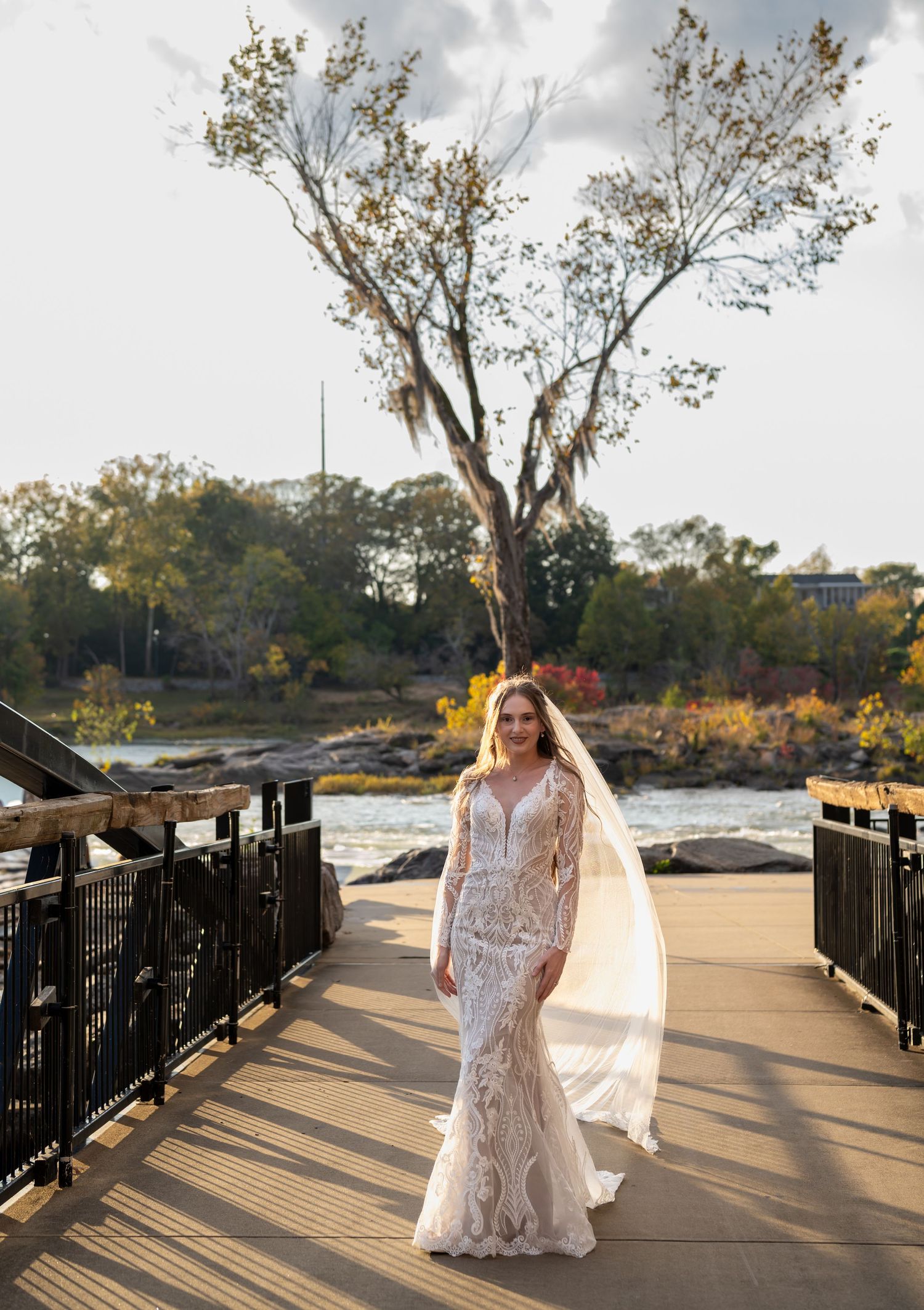 Beautiful bridal photos on a wooden boardwalk with dramatic shadows and autumn trees in the background.