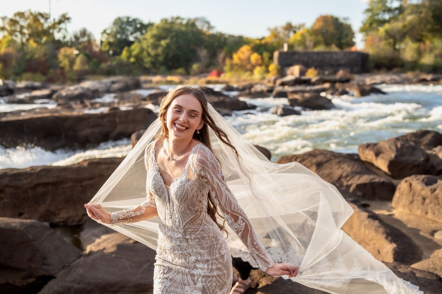 Dreamy bridal photography with billowing veil against natural waterfront setting.