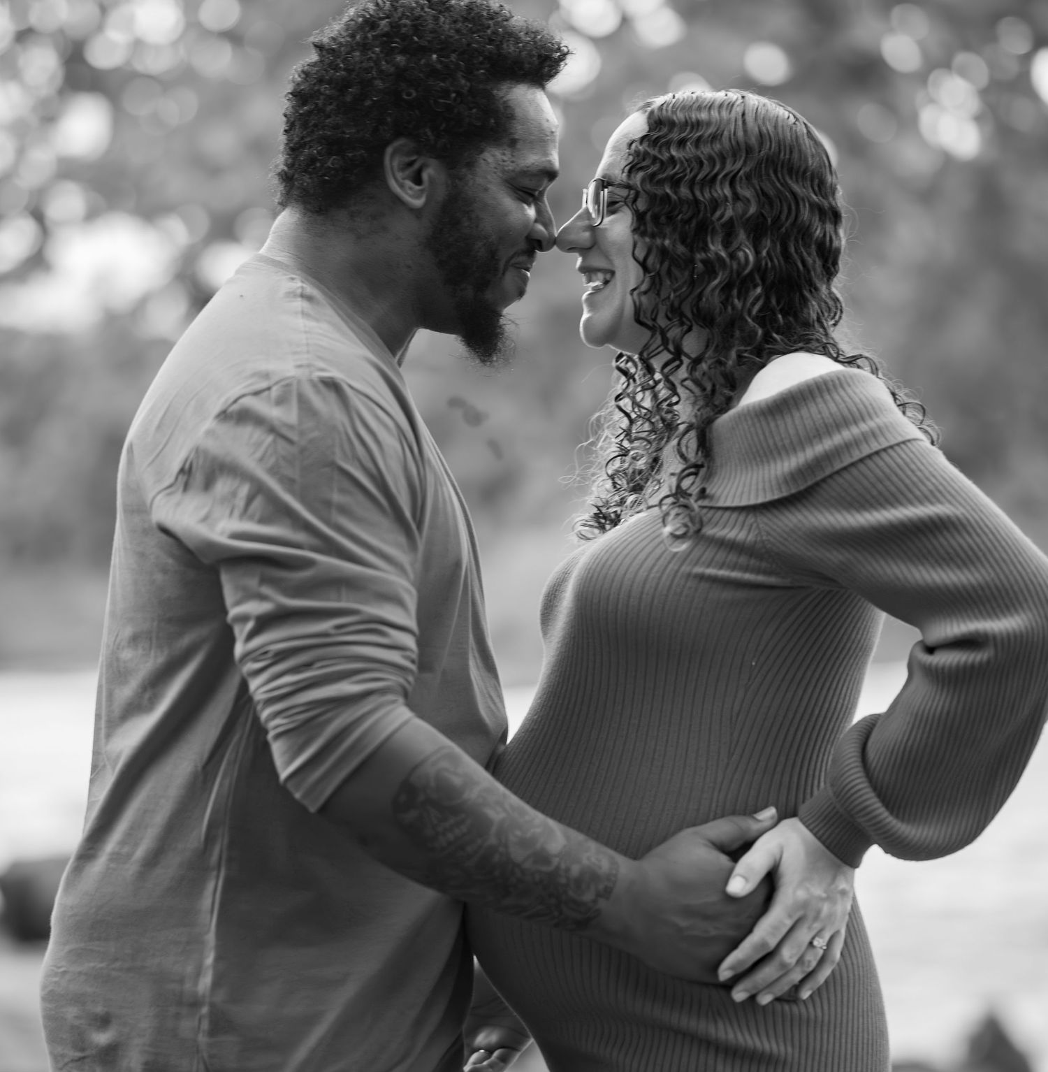 Black and white intimate portrait of a couple sharing tender moments outdoors.