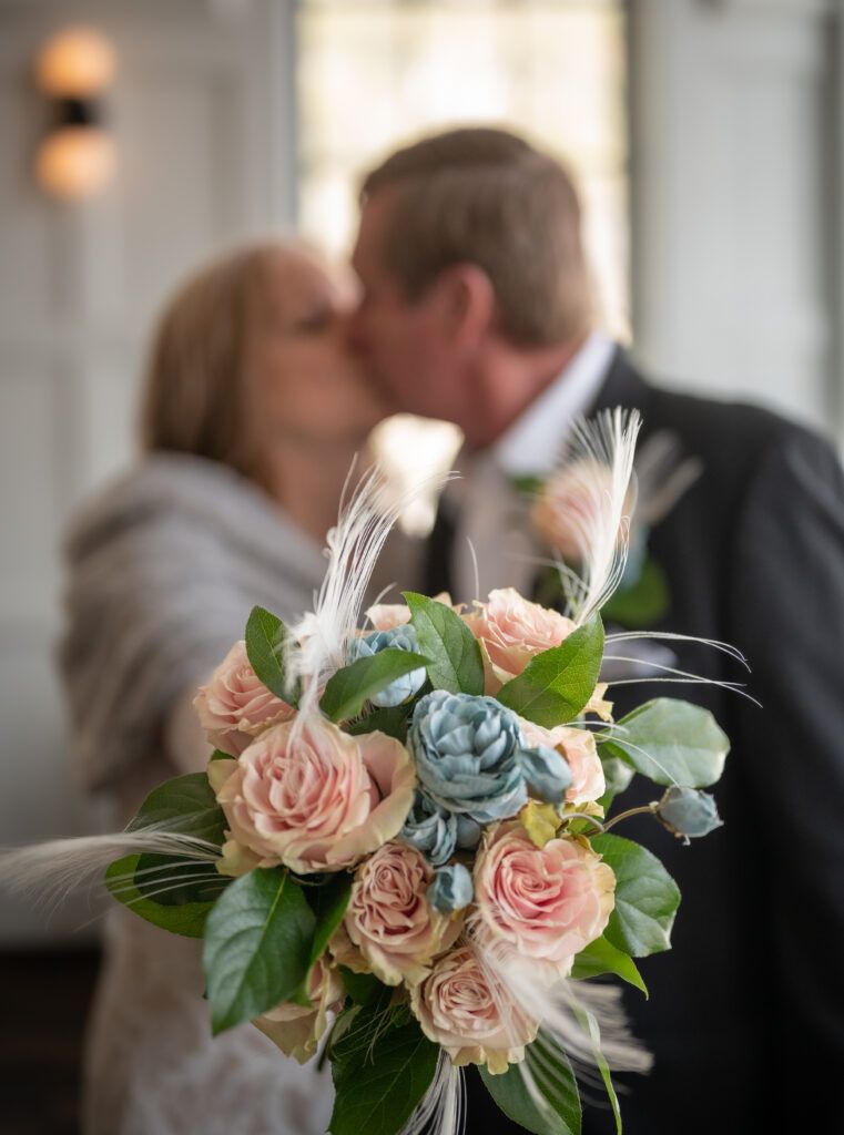 Up close photography of the brides bouquet. The couple is in the background  with a blurred effect to put the focus on the bouquet.