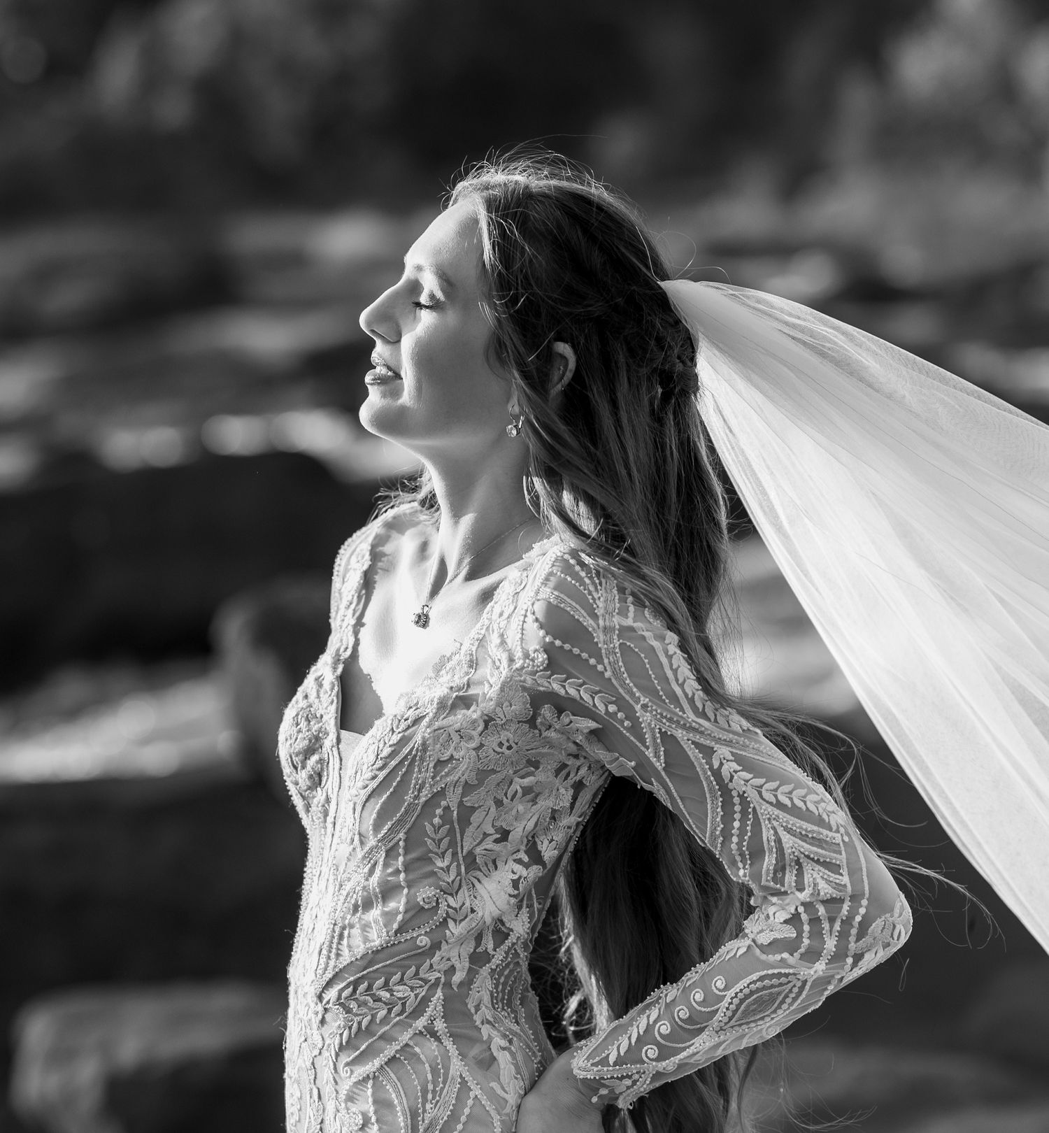 A black and white bridal portrait showcasing intricate lace details and flowing veil.