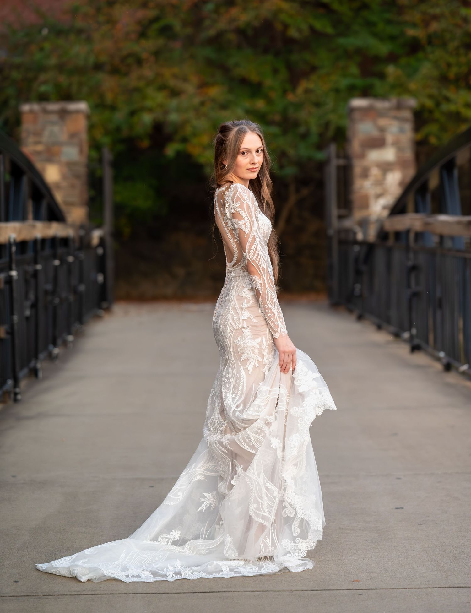 Wedding dress with flowing train photographed on stone pathway with iron railings.