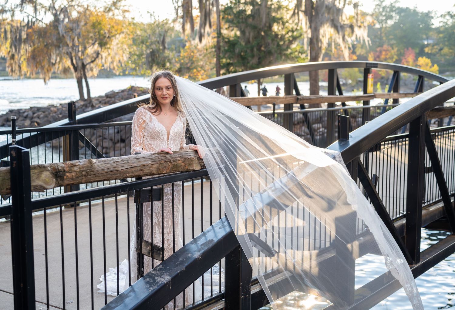 Romantic bridal photo on wooden bridge with flowing veil and Spanish moss in background.