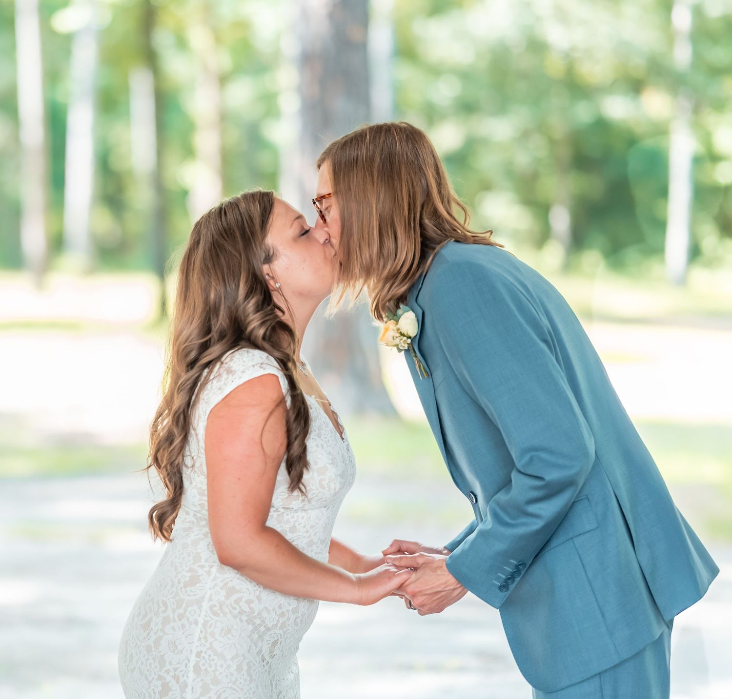 Wedding ceremony outdoors with couple exchanging vows under wooden pavilion.