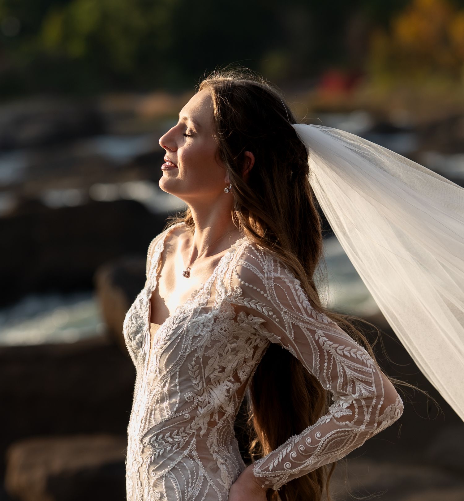 Elegant bridal portrait featuring a long veil flowing in the wind against a natural backdrop.