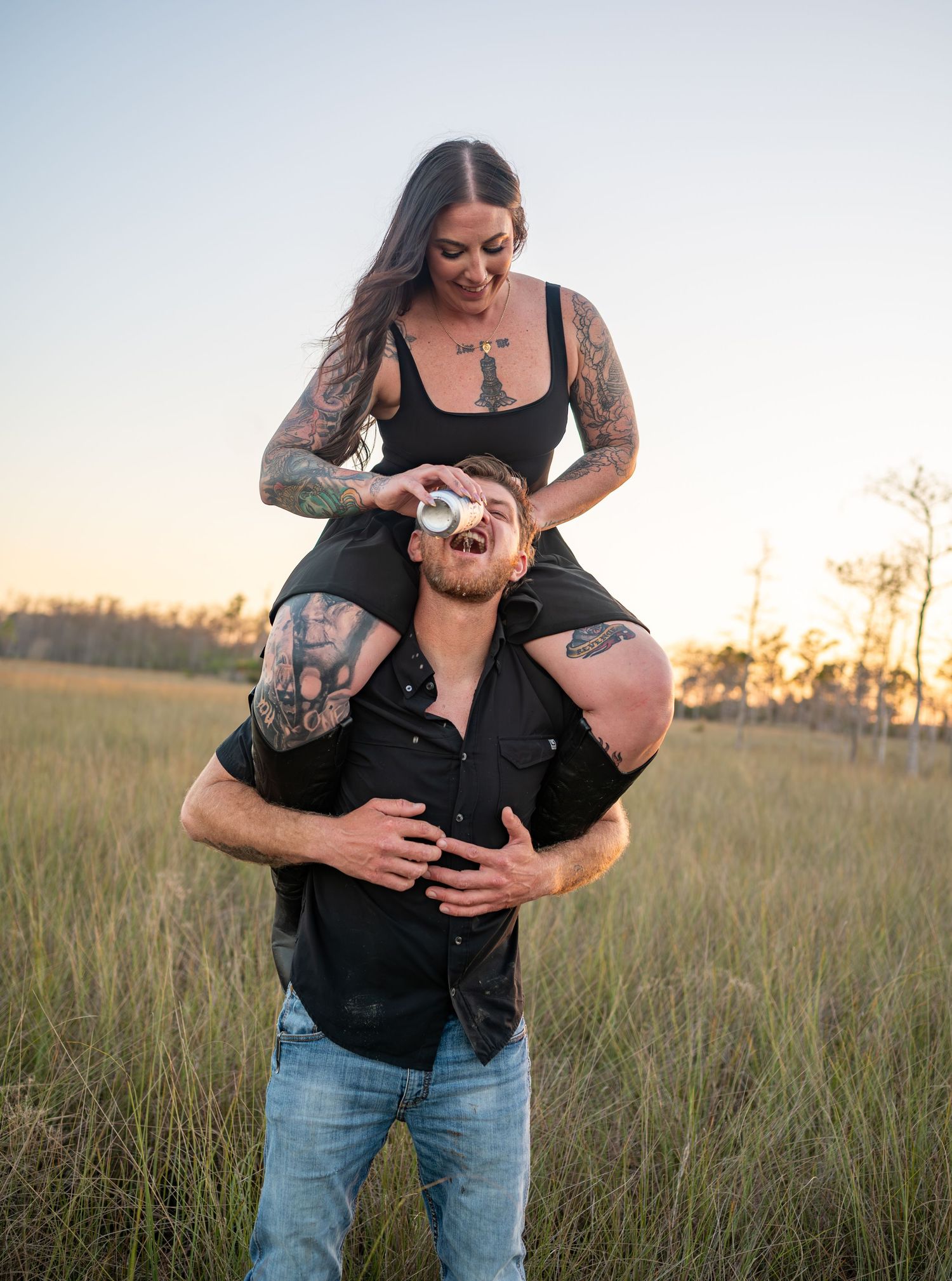 Romantic couple embraces in a sunlit field during golden hour photoshoot.
