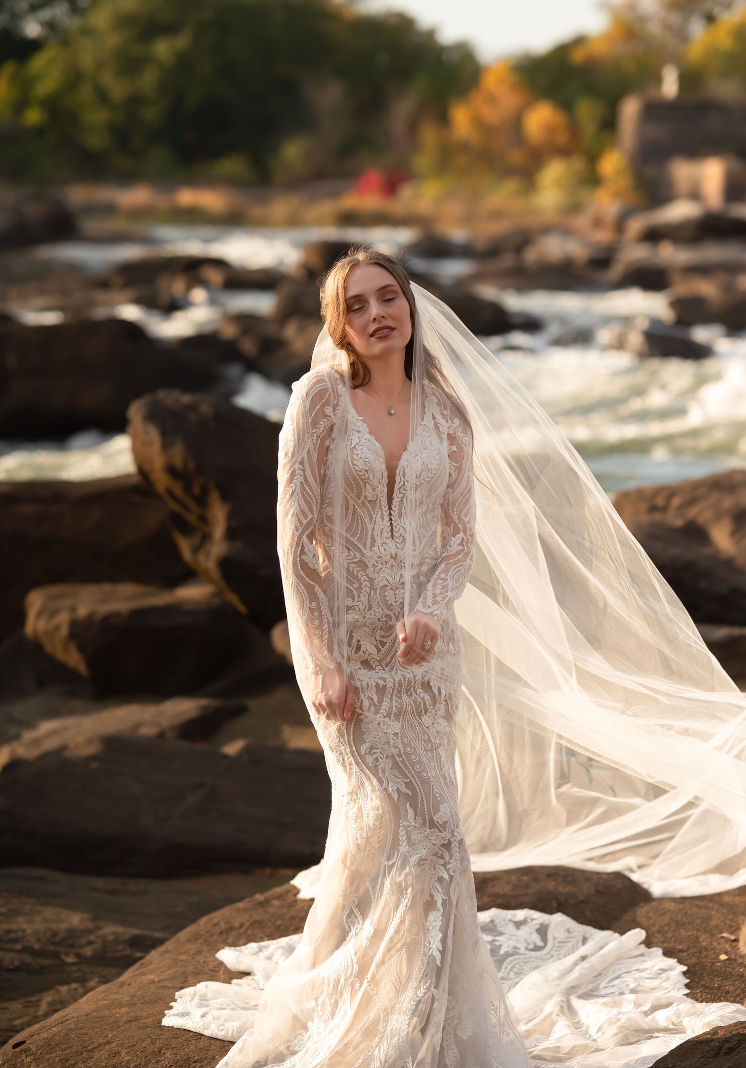 A romantic bridal session on rocky terrain with a flowing cathedral veil catching the autumn sunlight.