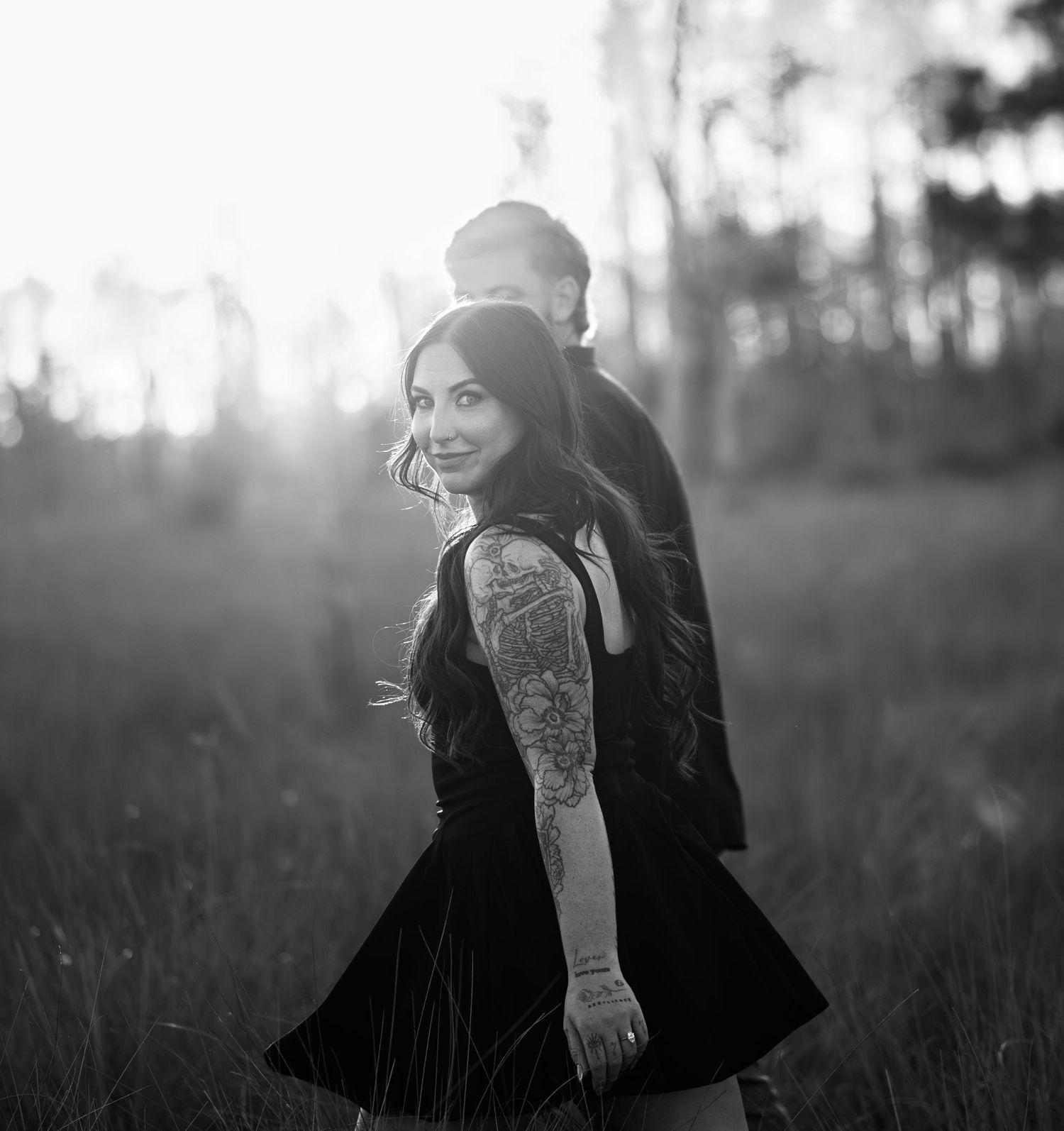Black and white portrait of a couple sharing an intimate moment in a field.