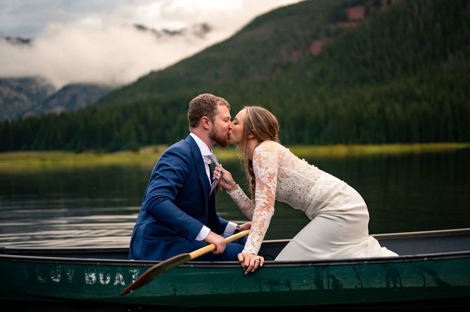 Romantic couple shares intimate moment in canoe on mountain lake.