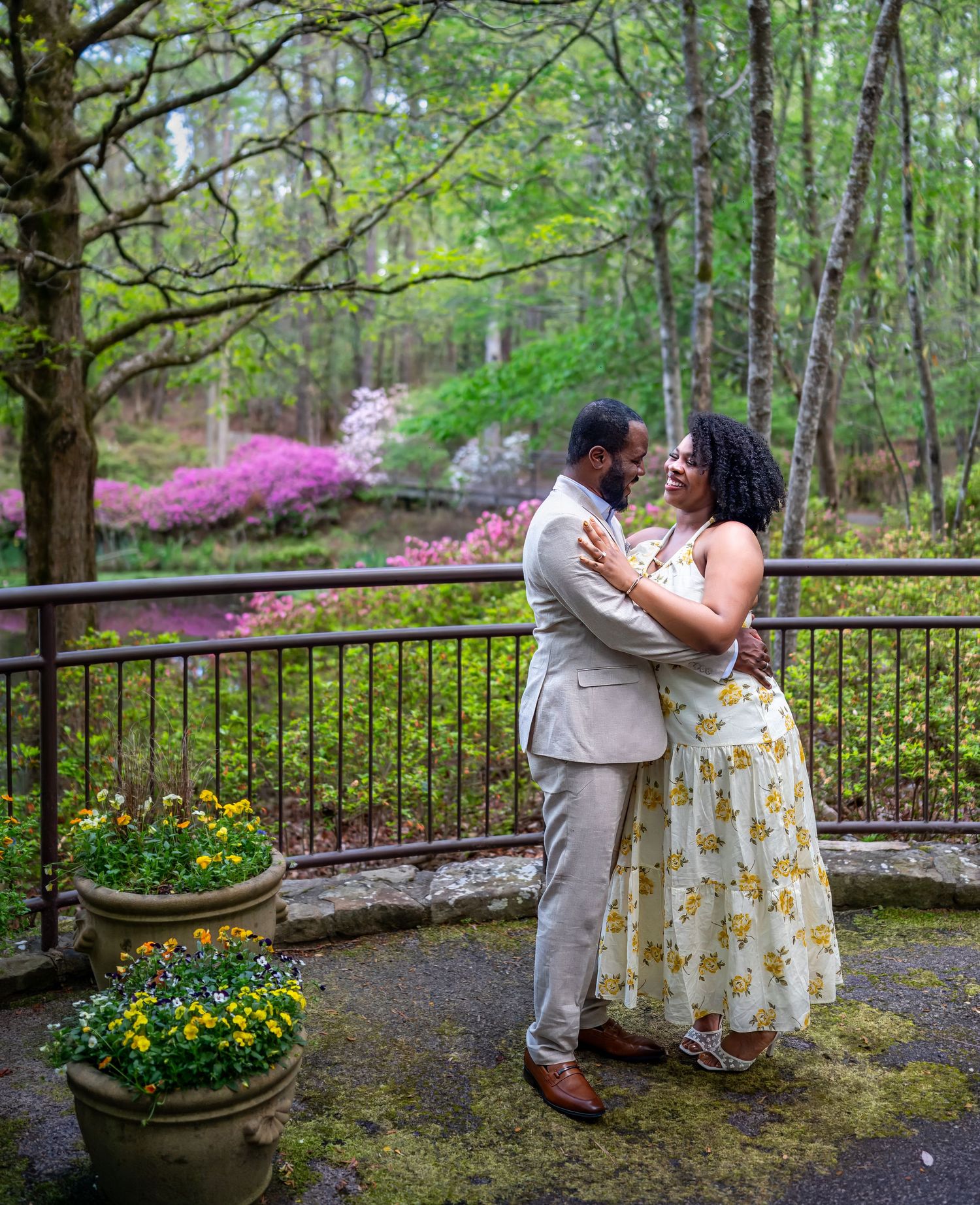 Happy couple sharing a romantic moment on a stone terrace with colorful azaleas and flowers.