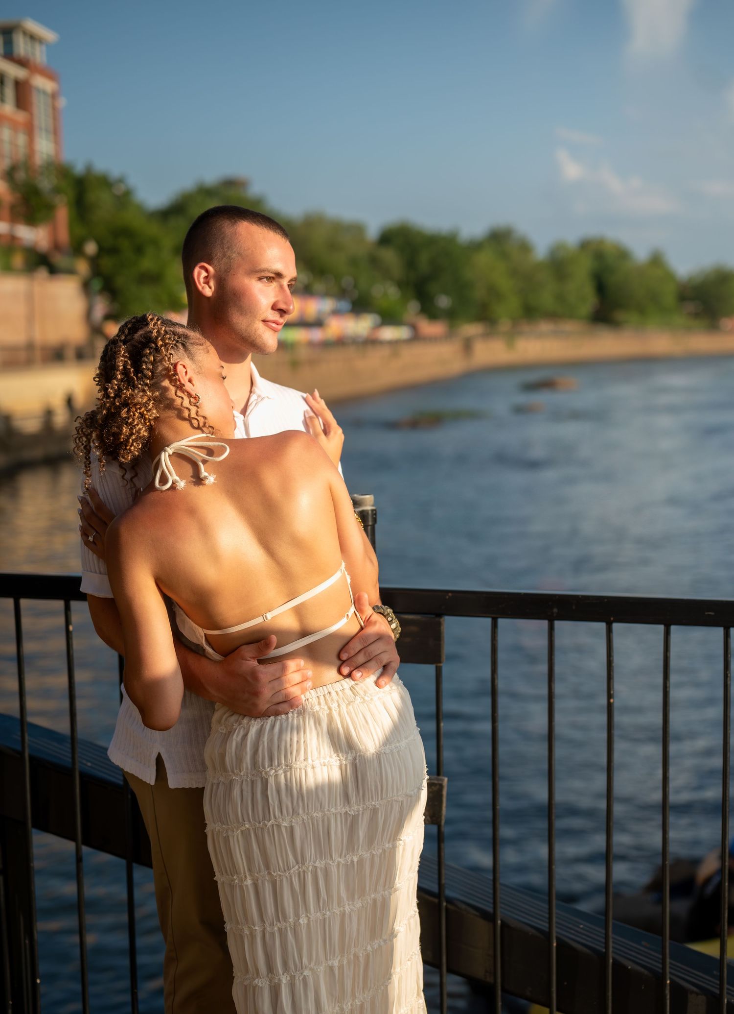 A series of romantic photos showing a couple embracing against a railing overlooking a scenic waterfront at sunset.