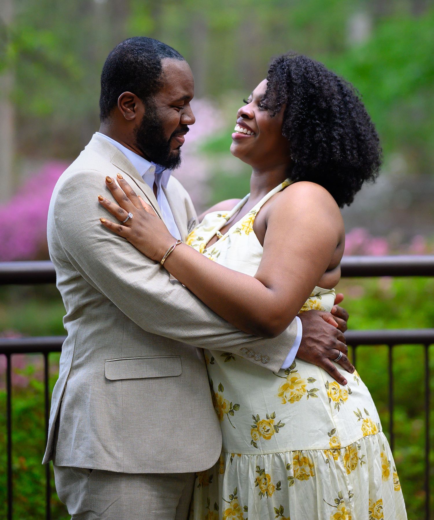 A couple sharing a joyful moment, laughing and embracing in a beautiful garden setting.