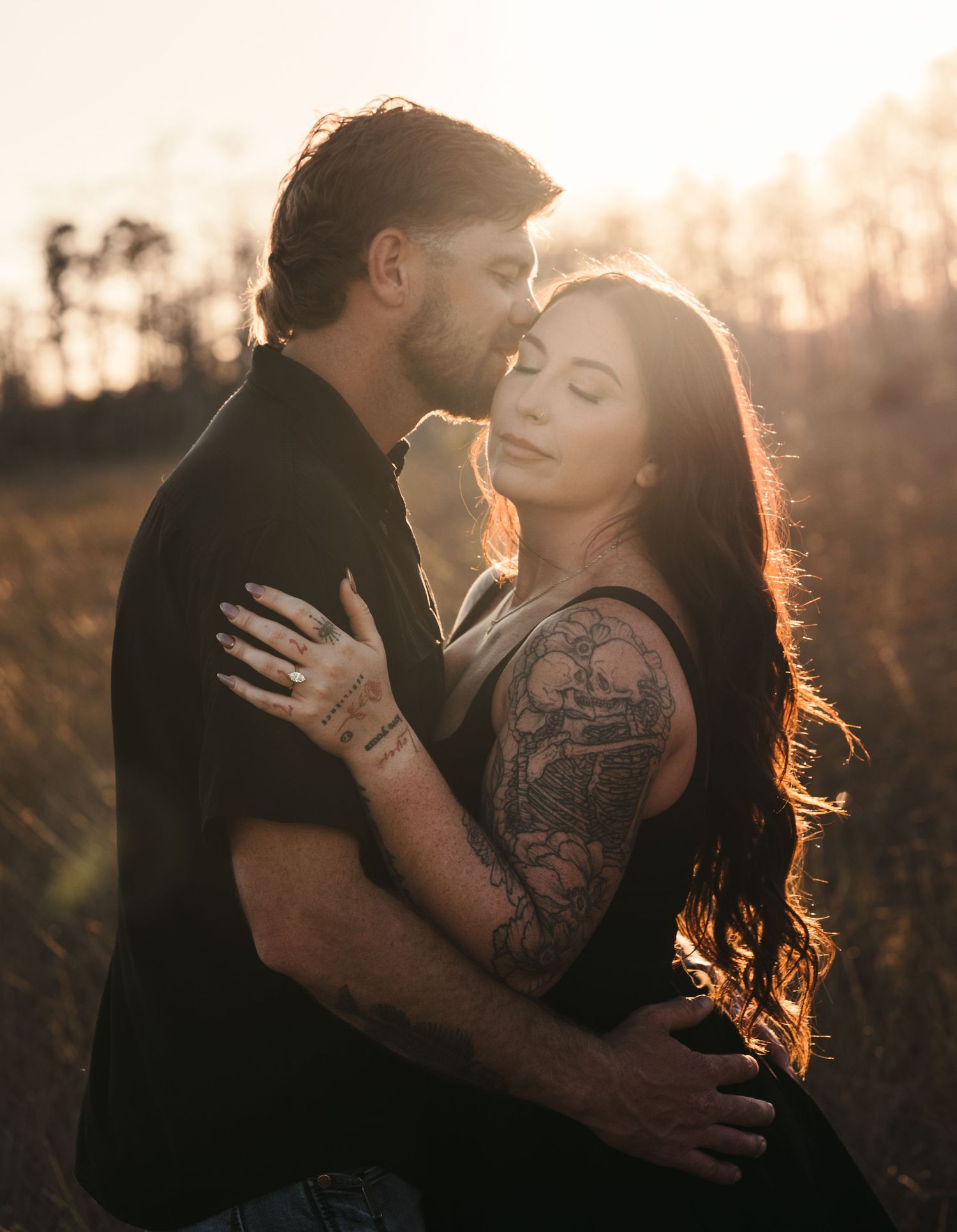 Backlit couple embracing in golden sunlight during outdoor portrait session.