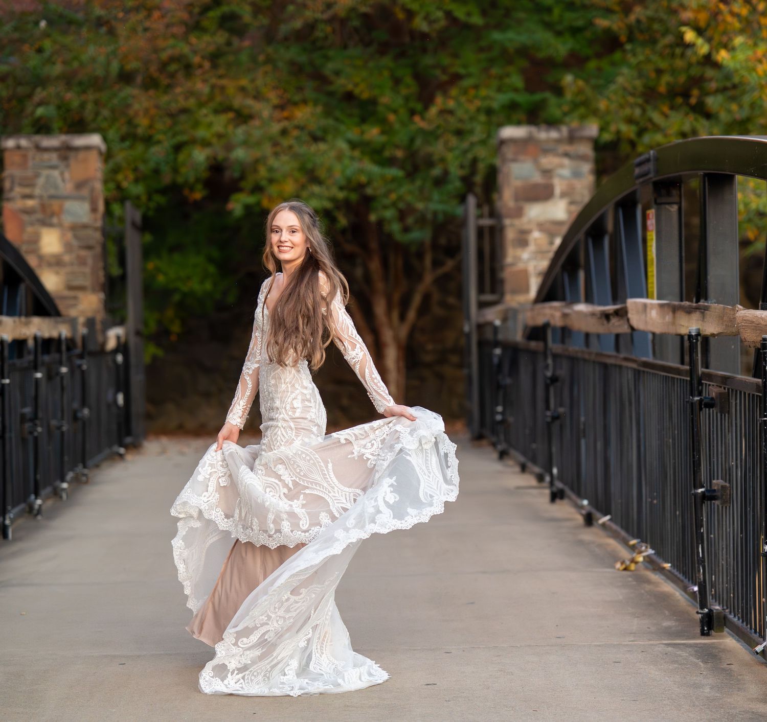 A joyful bridal portrait on a bridge featuring a lace wedding gown with flowing skirt.