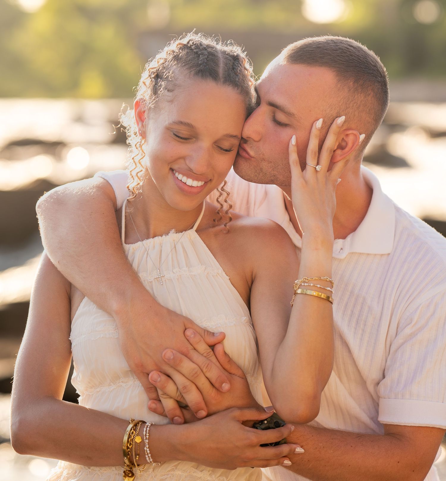 A romantic couple shares intimate moments during a golden hour photoshoot by the water.