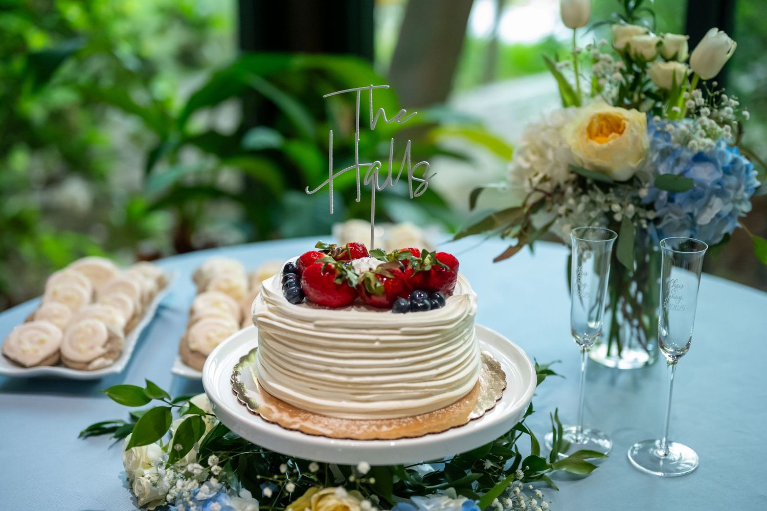 Wedding reception table decorated with fresh flowers, berries and stacked white plates.