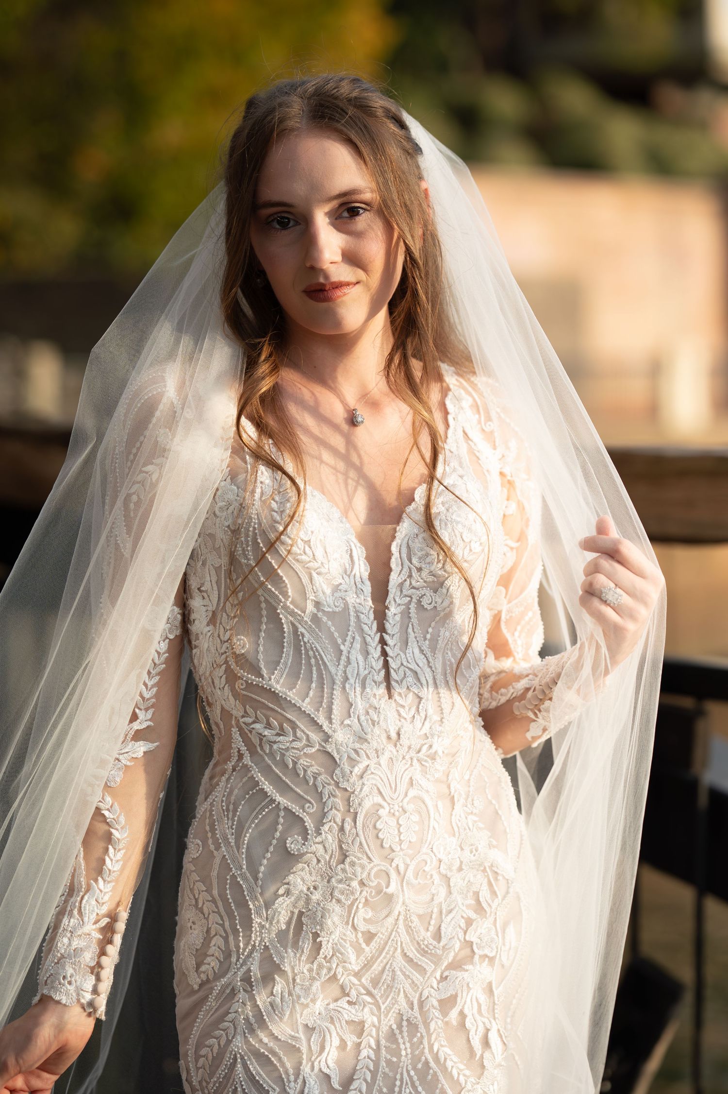 A romantic bridal portrait in golden light featuring delicate lace details and sheer veil.