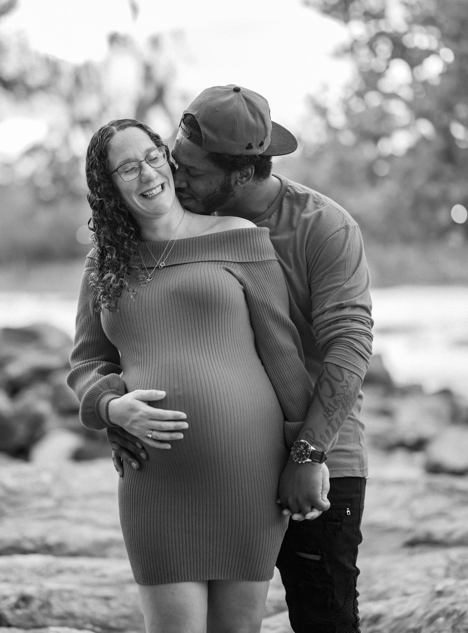 Intimate black and white maternity photo of couple sharing a tender moment on rocky terrain.