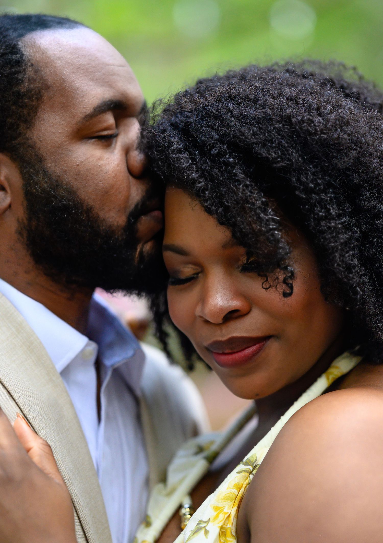 Man tenderly kisses woman on the forehead in a romantic outdoor portrait.