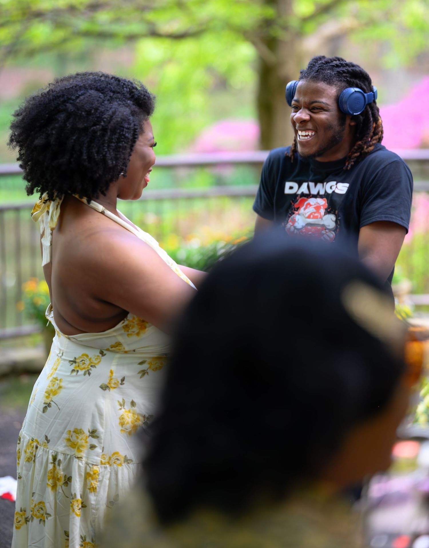 DJ with headphones laughing with guest at outdoor wedding reception.