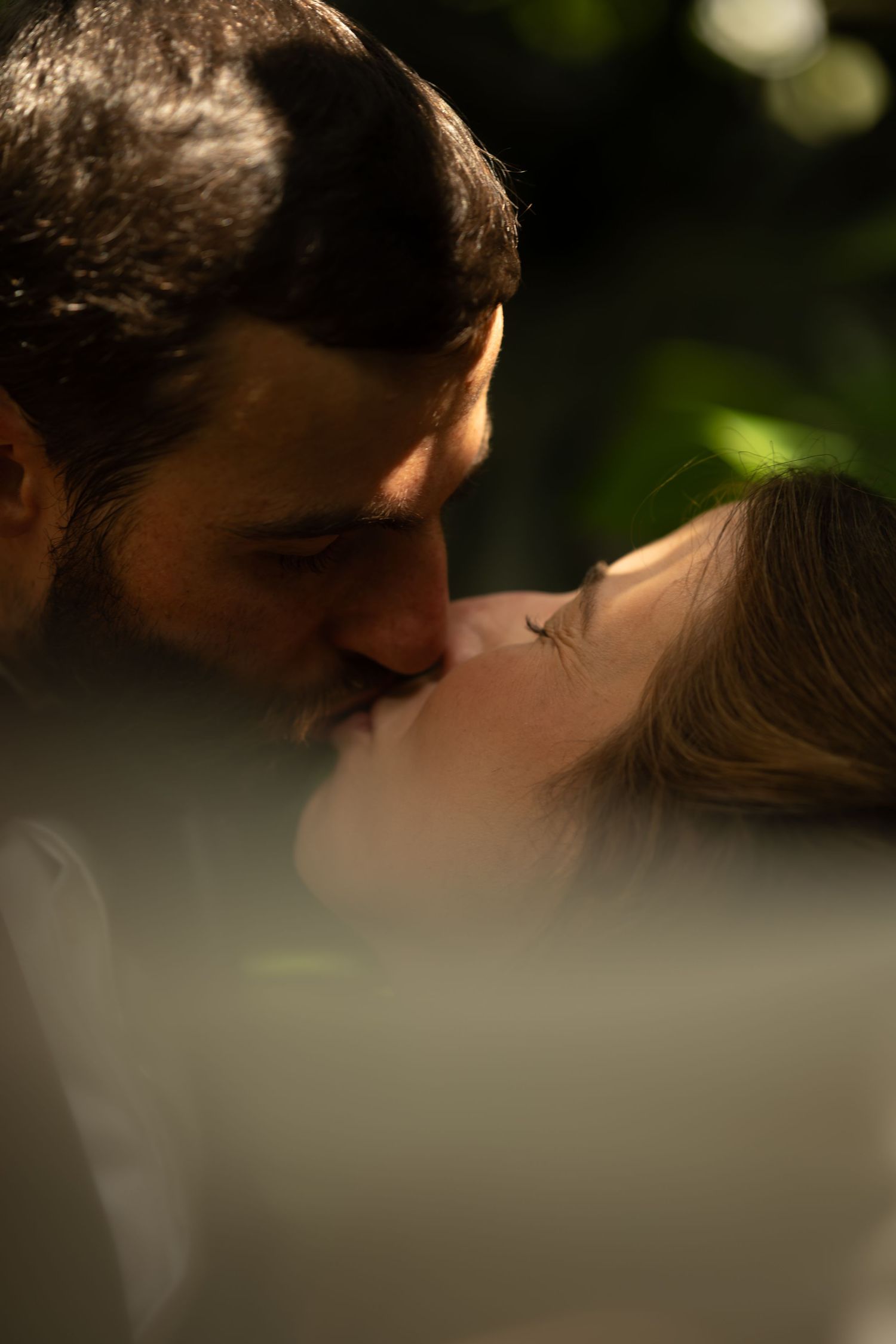 A romantic couple sharing an intimate moment with soft bokeh lighting in the background.