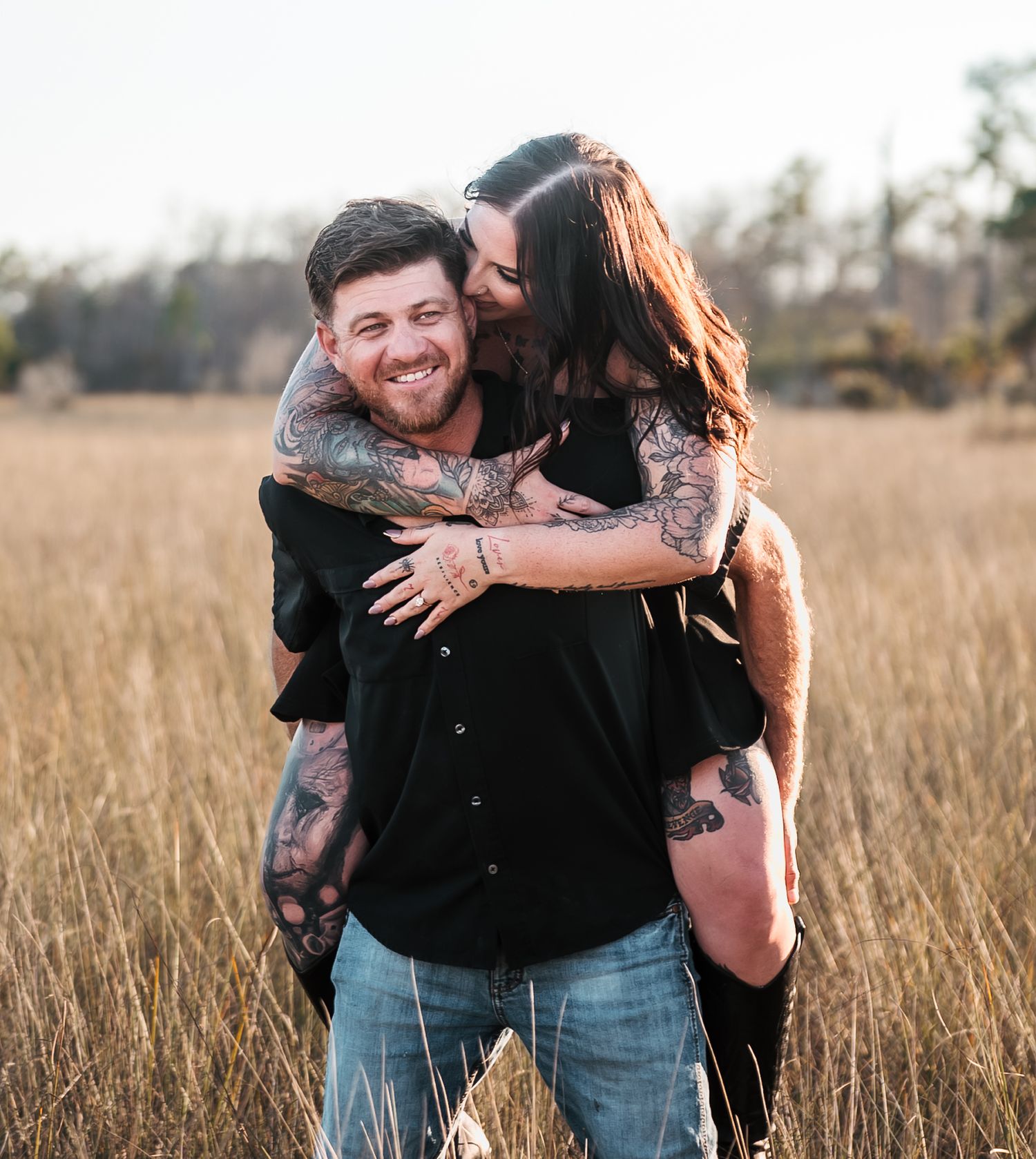 Couple embraces in a golden field at sunset, creating a romantic silhouette against the warm light.