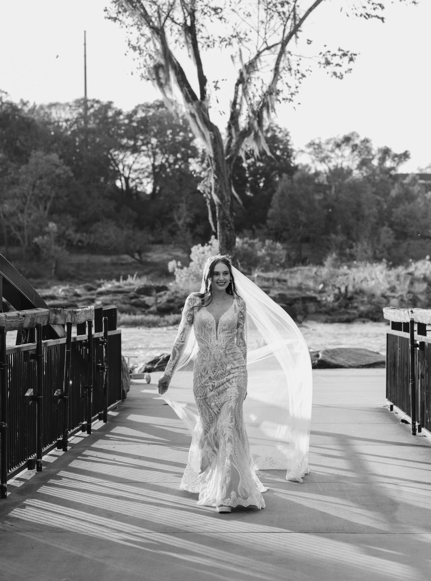Black and white photos of a flowing wedding dress on a bridge with dramatic movement.