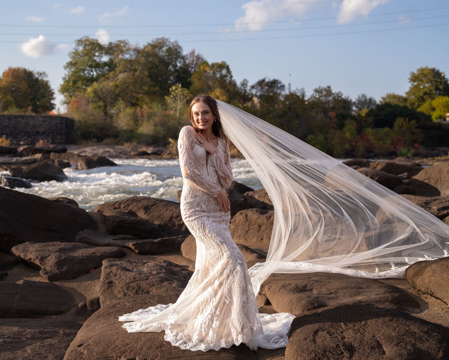 An elegant bridal portrait on rocky terrain with a flowing veil catching the wind.
