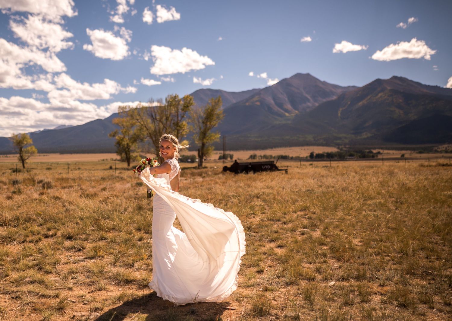 Wedding dress flowing in the wind against desert mountain landscape with blue skies.