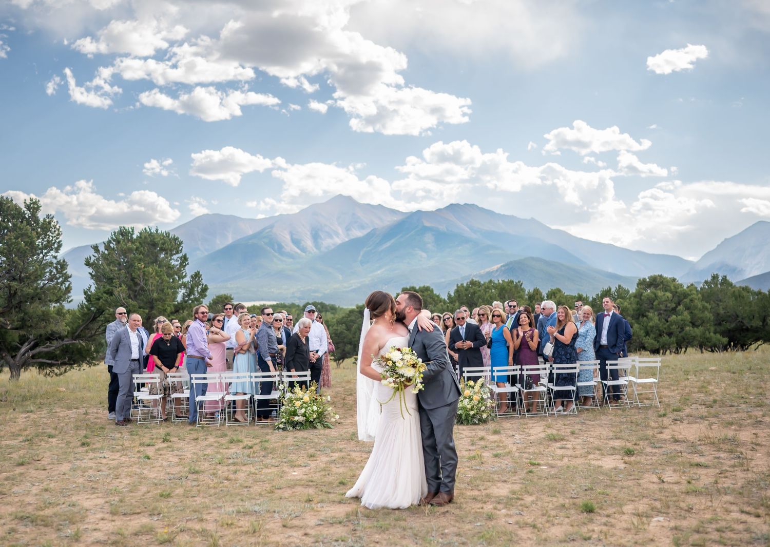 Wedding ceremony setup with chairs facing mountain vista under blue skies.