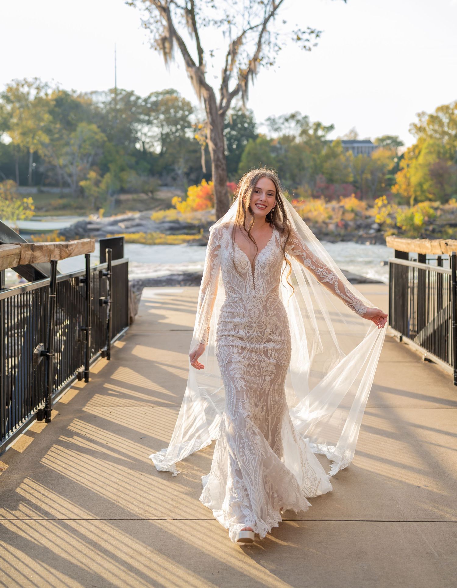 Sunlit bridal portraits on wooden boardwalk with flowing veil and fitted lace dress.
