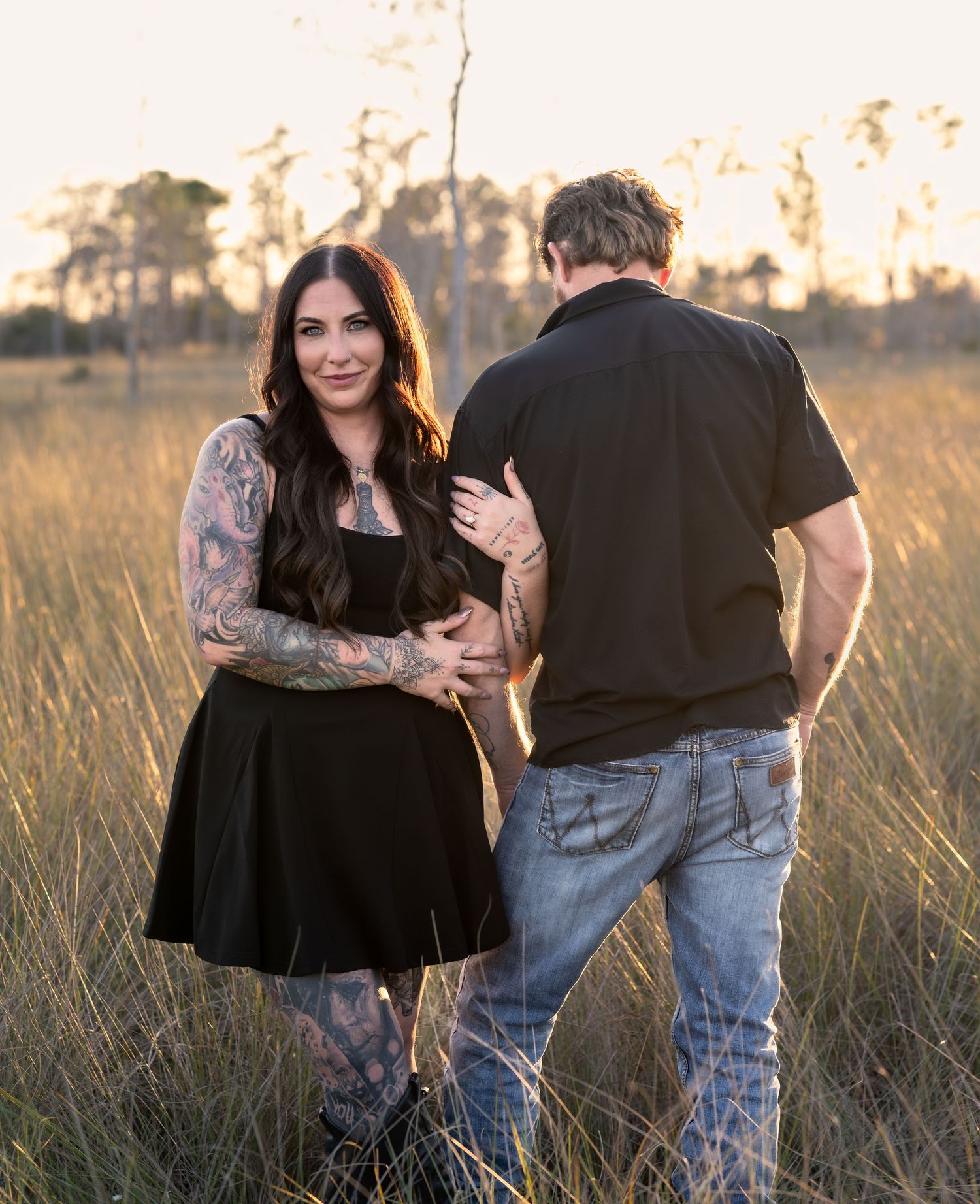 A couple embraces in a golden field during sunset creating a romantic silhouette against the warm evening light.