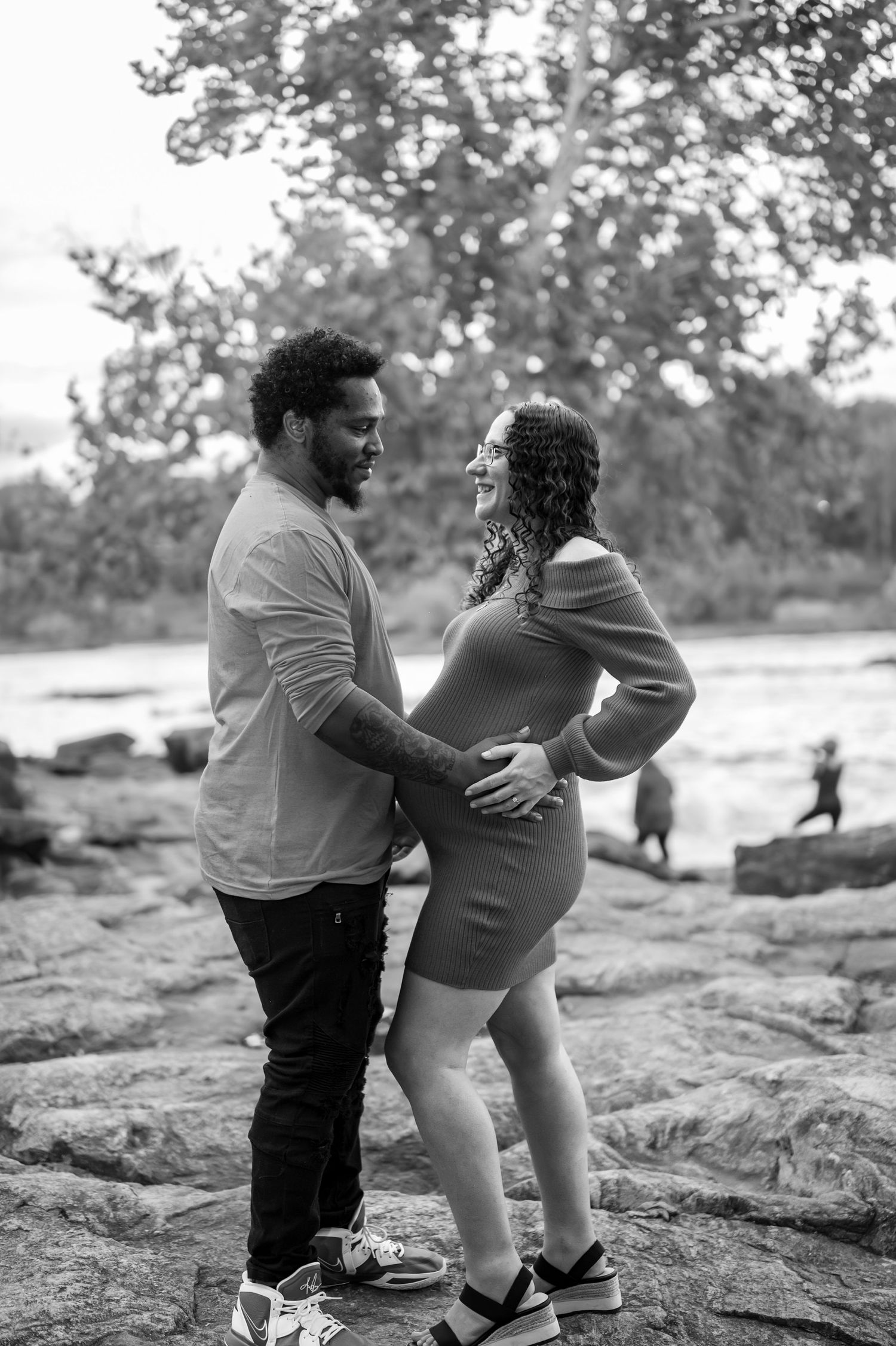 Black and white maternity photos showing tender family moments on rocky terrain.