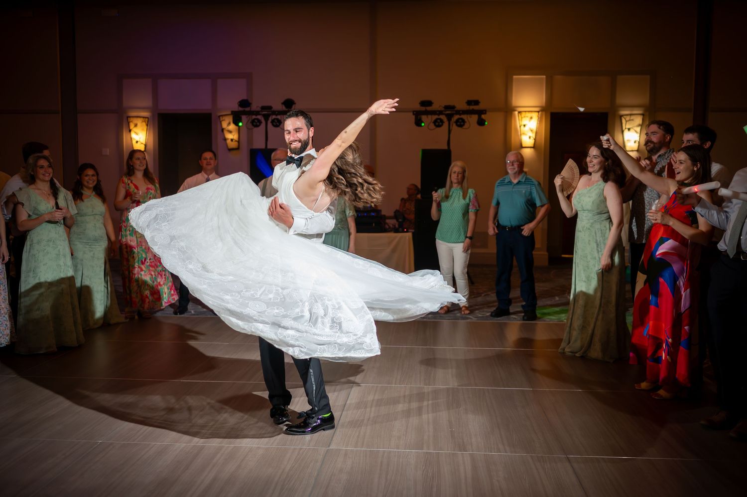 Joyful dancing and celebration on dimly lit ballroom dance floor at wedding reception.