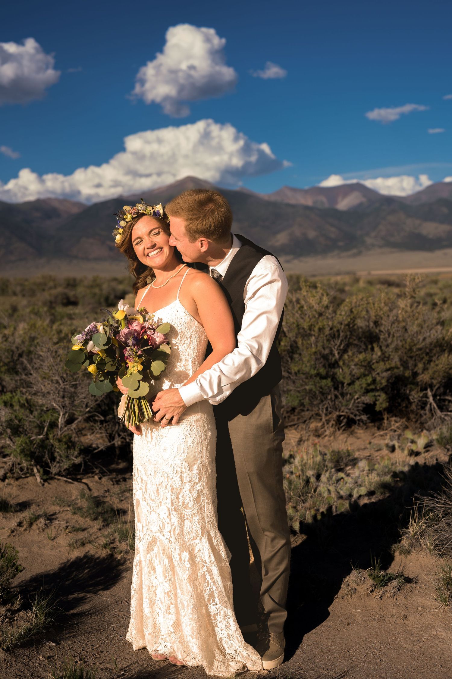 Desert wedding portraits with dramatic mountain landscape and lace dress details.