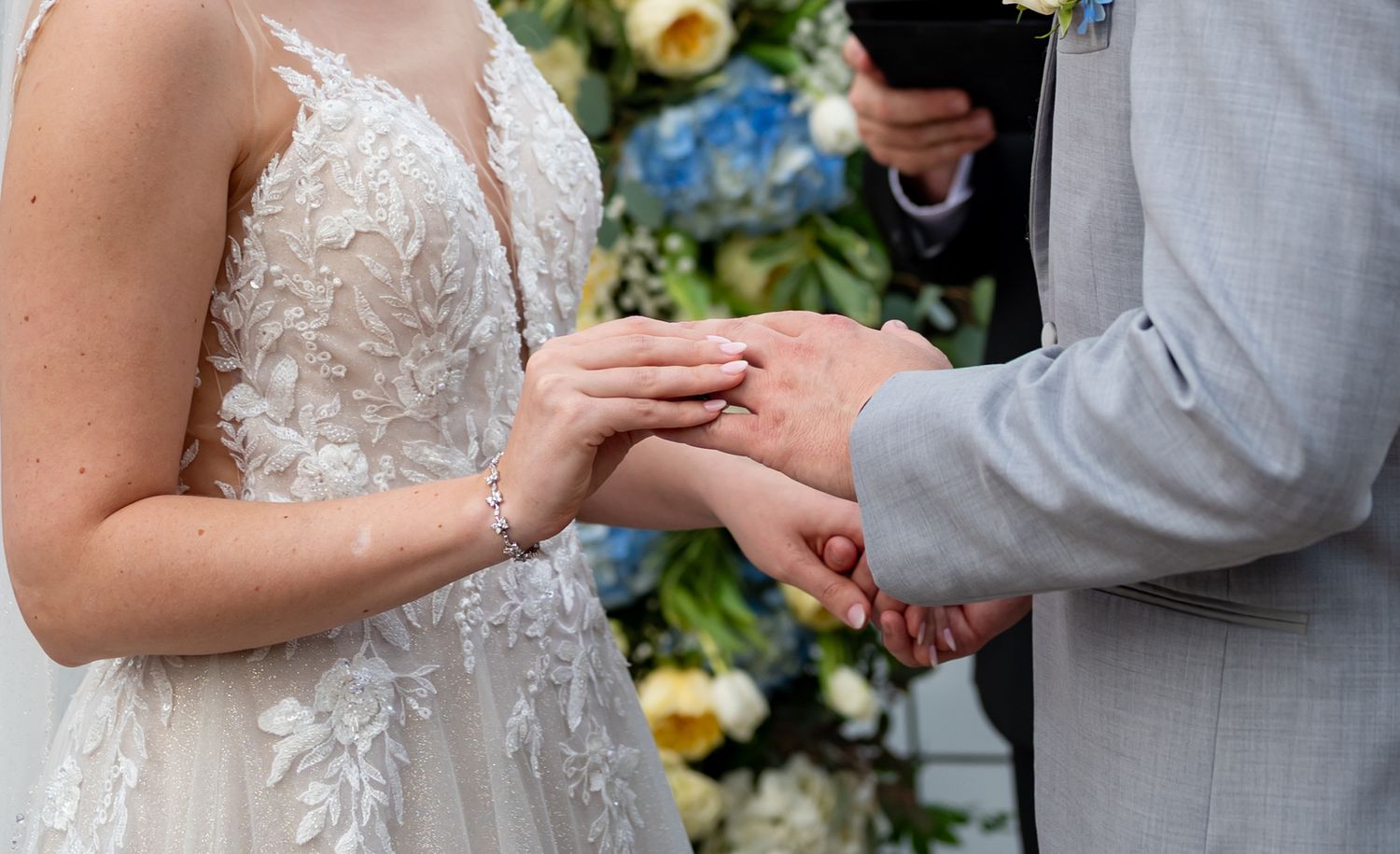 Close-up of ring exchange during lakeside dock wedding ceremony.