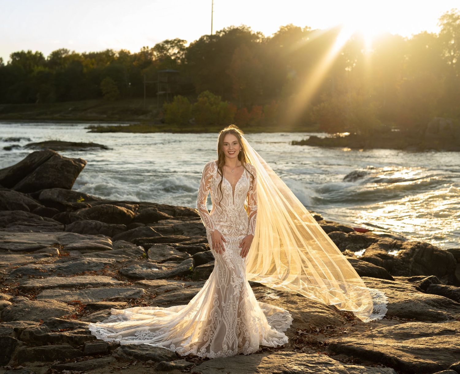 Sunset bridal session on rocky coastline with flowing veil catching golden light.
