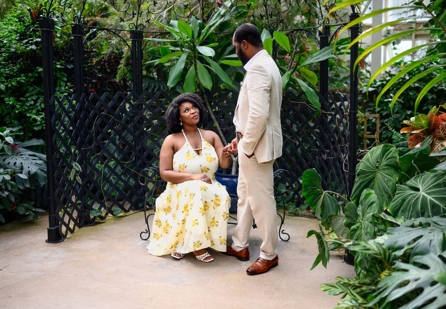 A couple shares a quiet intimate moment in a lush tropical garden during their engagement photo session.