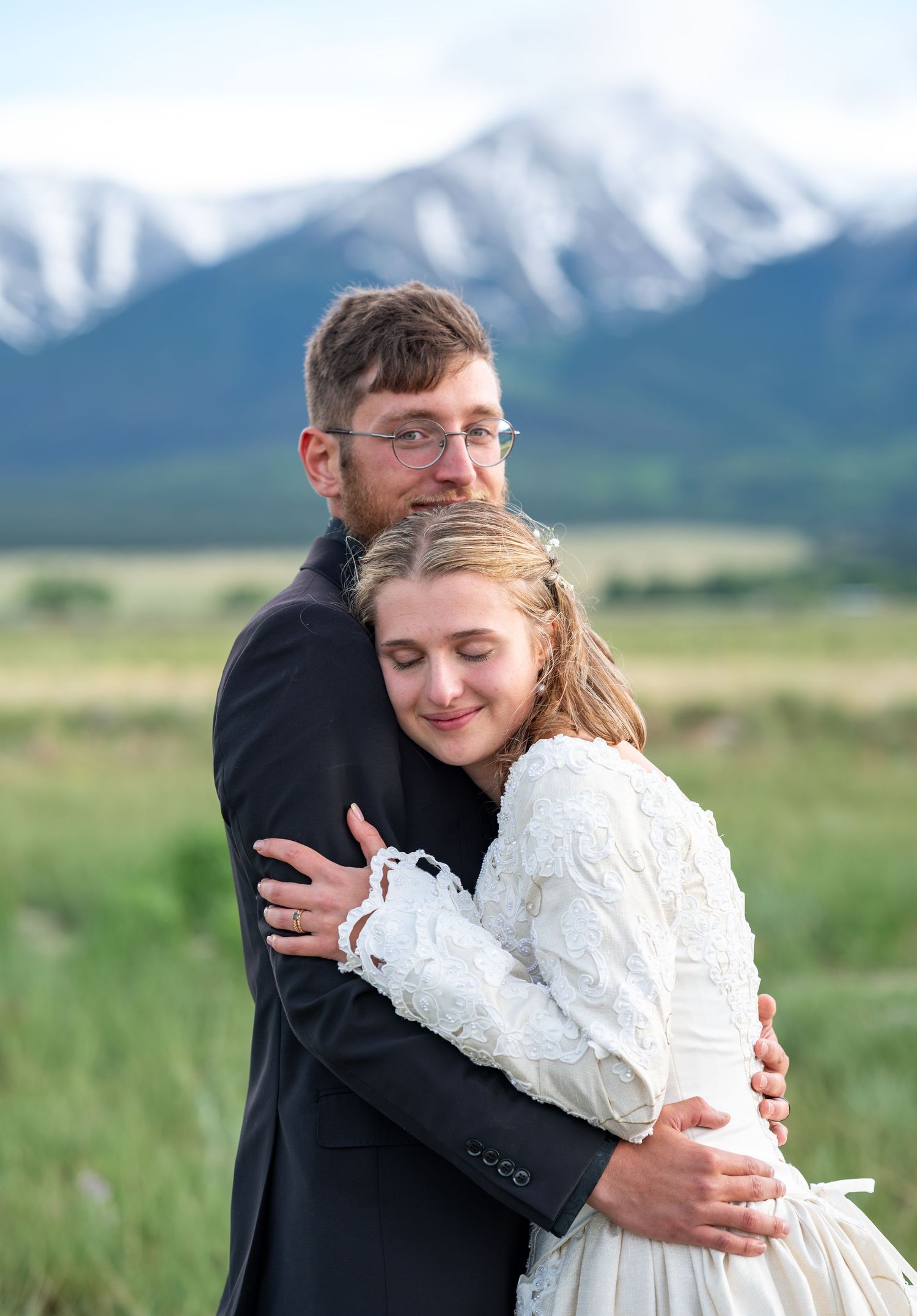 Couple sharing intimate embrace against mountain landscape backdrop.