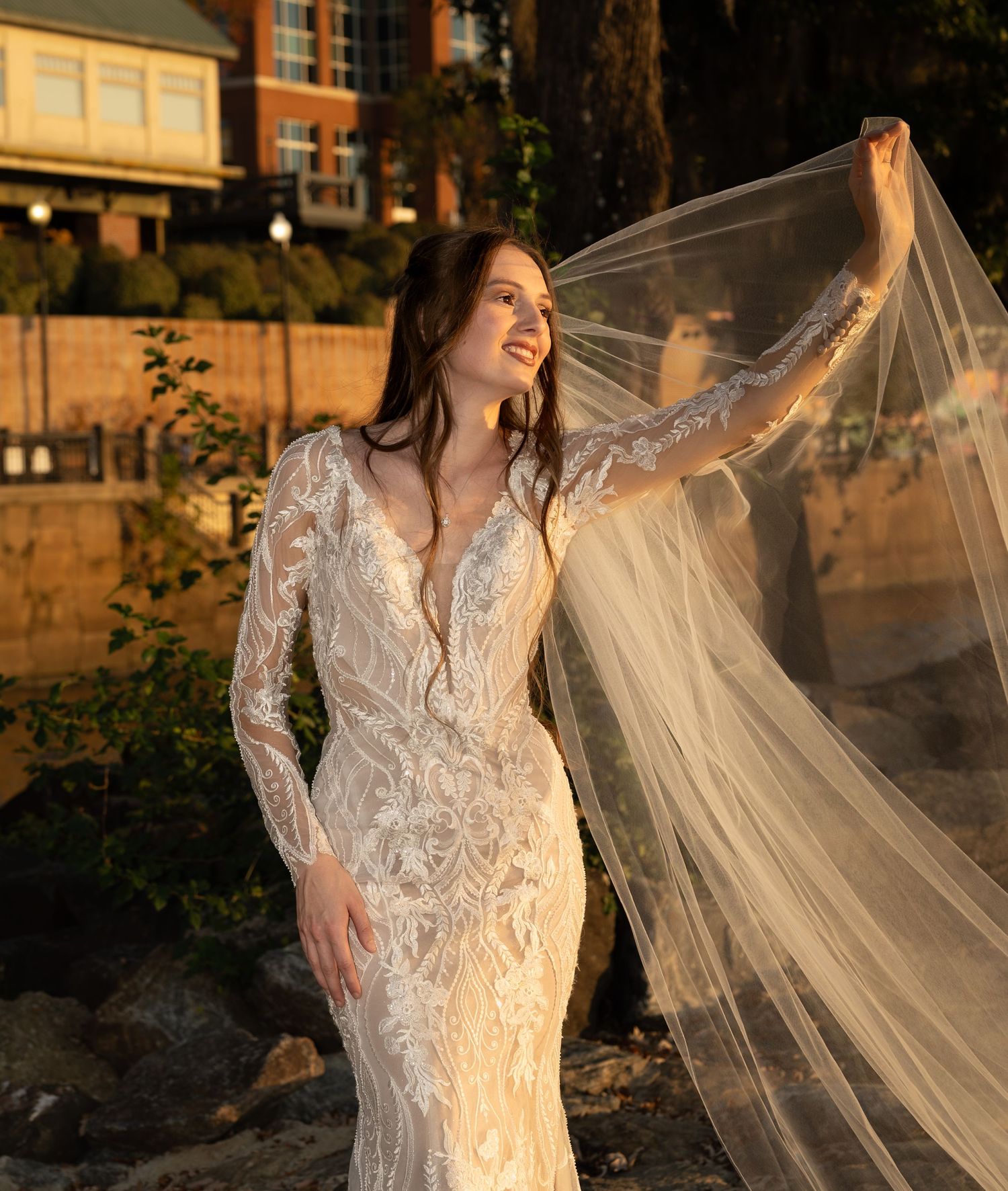 A romantic bridal portrait at golden hour featuring an intricate lace gown with a flowing veil.