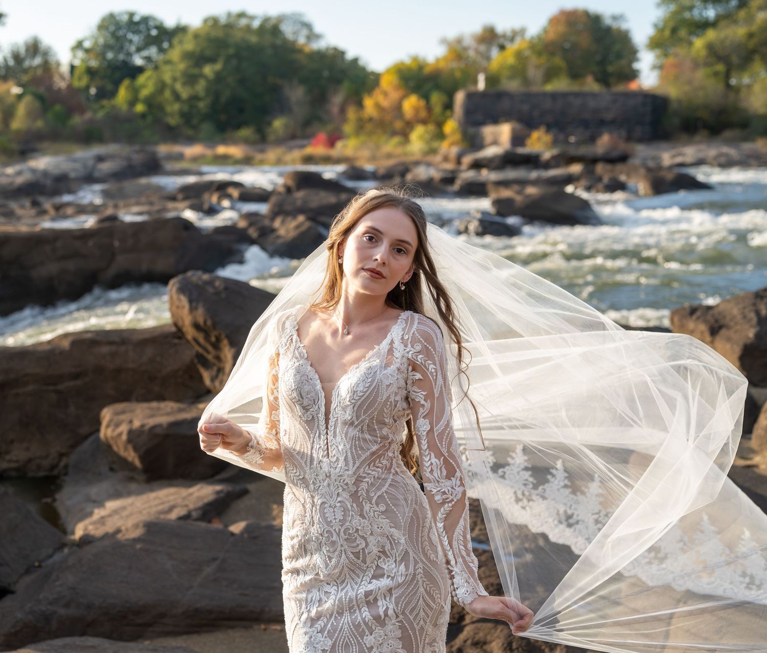 Ethereal bridal portrait with a flowing veil captured against a natural waterfall backdrop.