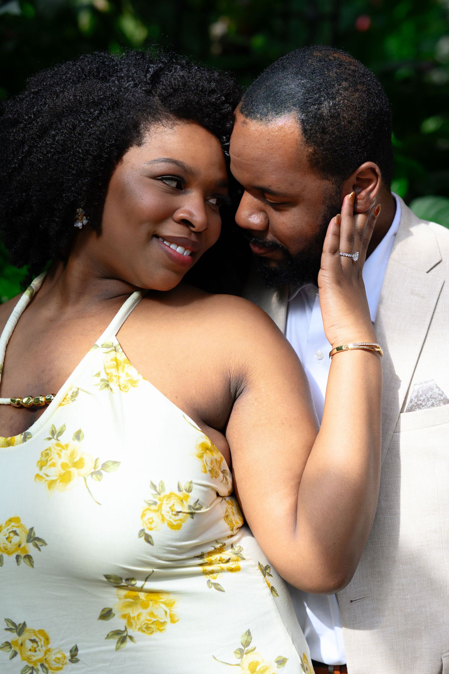 Close romantic portrait of couple touching foreheads tenderly, woman smiling in yellow floral halter dress.