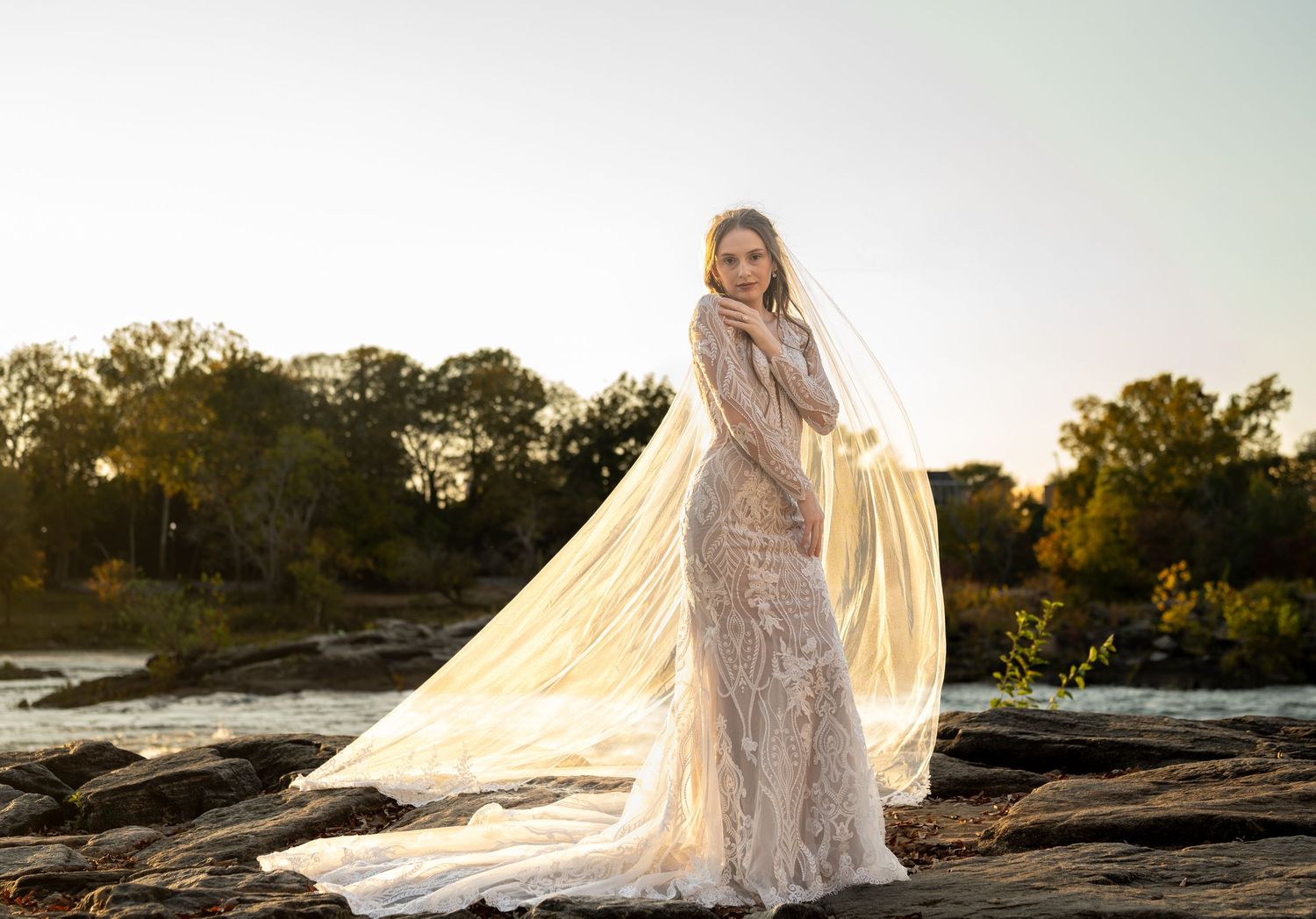 Ethereal bridal photography on rocky landscape during golden hour with flowing veil.
