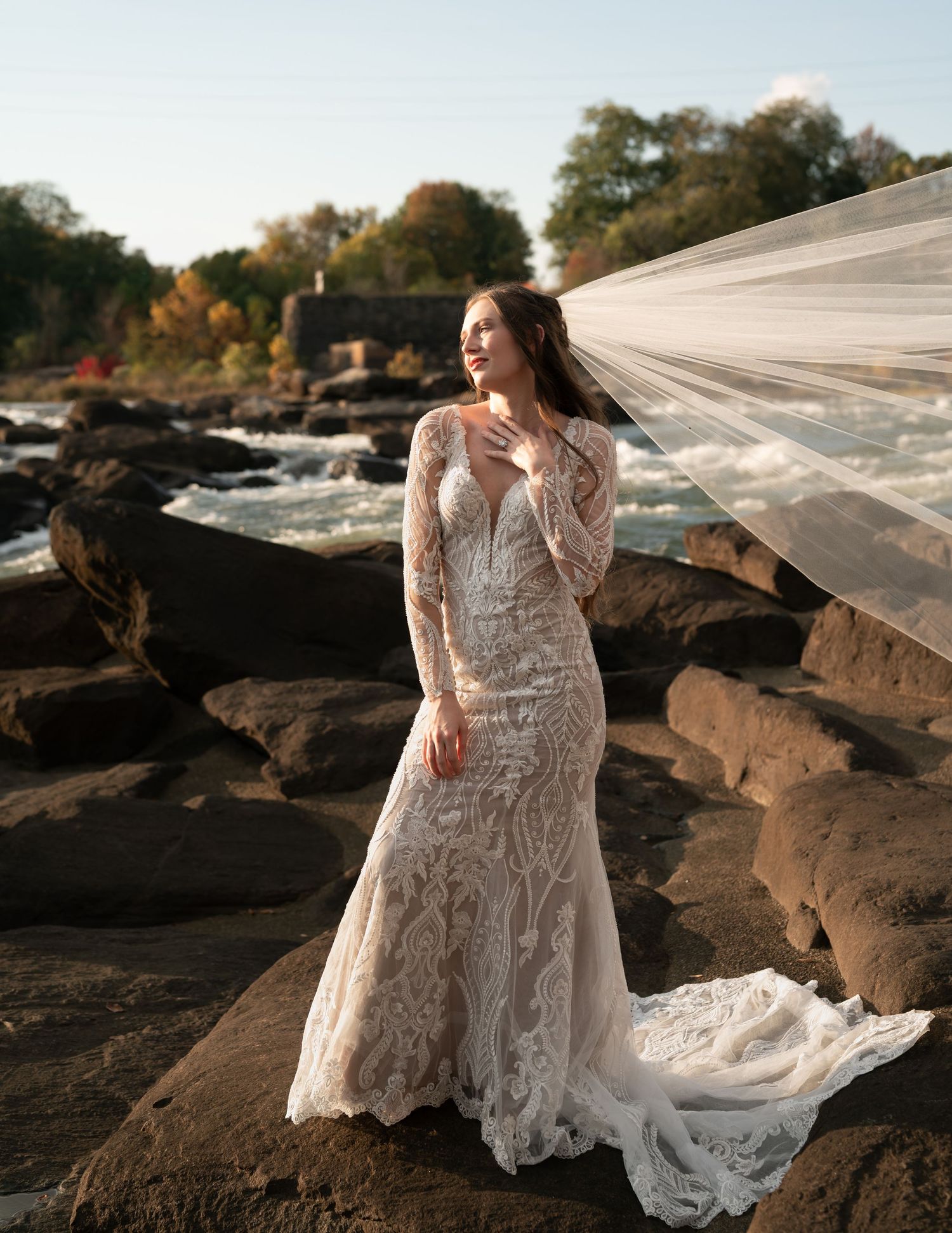 A beautiful wedding dress with intricate lace details photographed on rocky terrain at sunset.