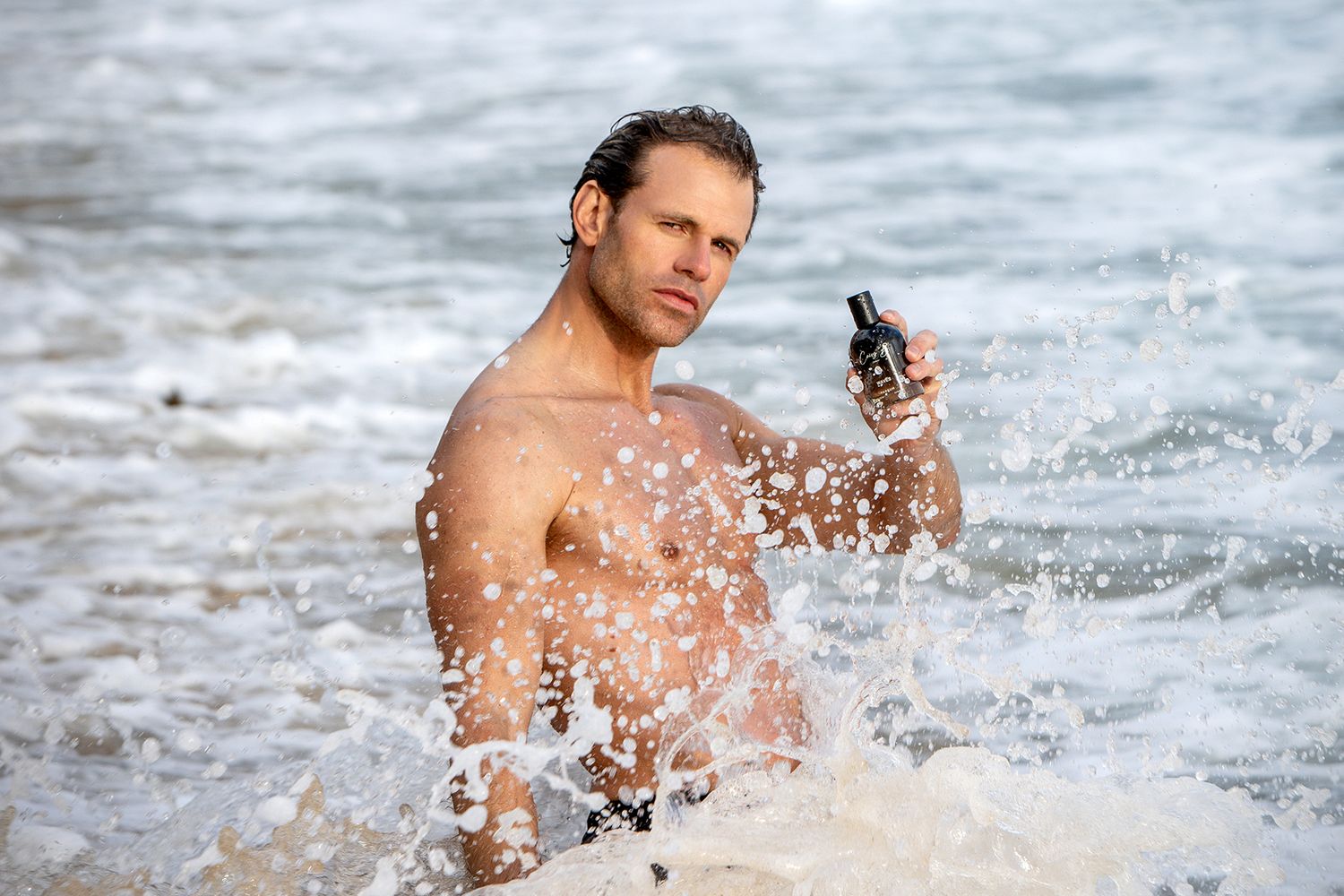 Athletic person moves quickly through splashing water on a beach during an energetic workout or training session.