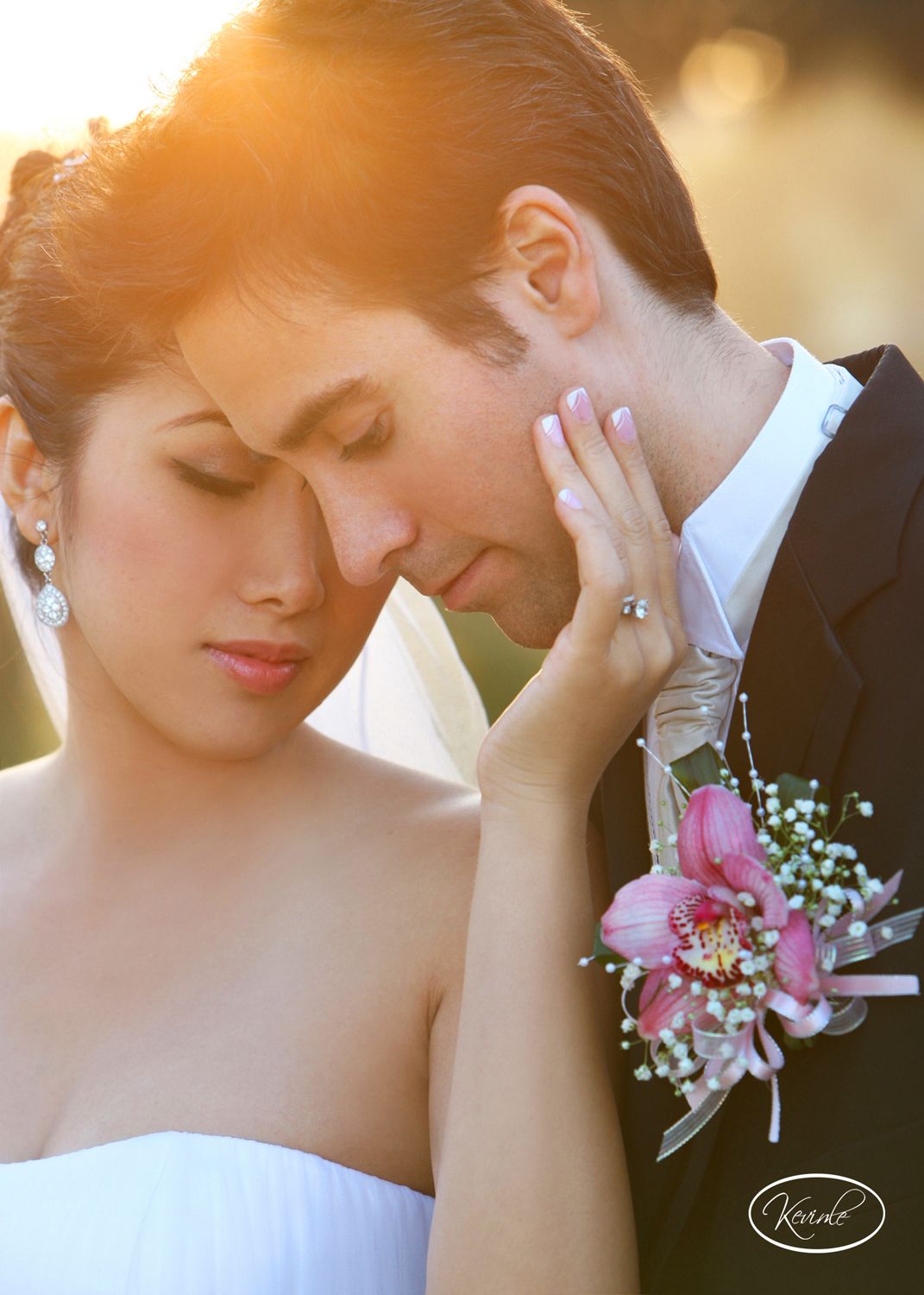 Romantic sunset portrait of newlyweds with pink corsage in golden light.