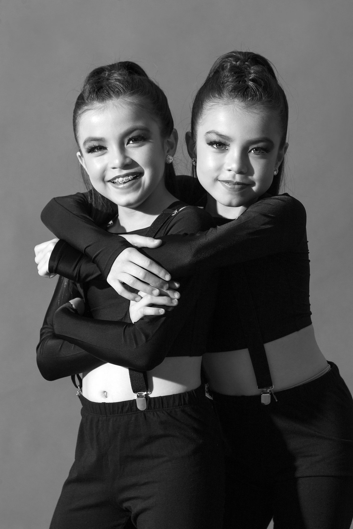 Series of black and white photos showing two people in dark clothes embracing and hugging in different poses against a gray backdrop.
