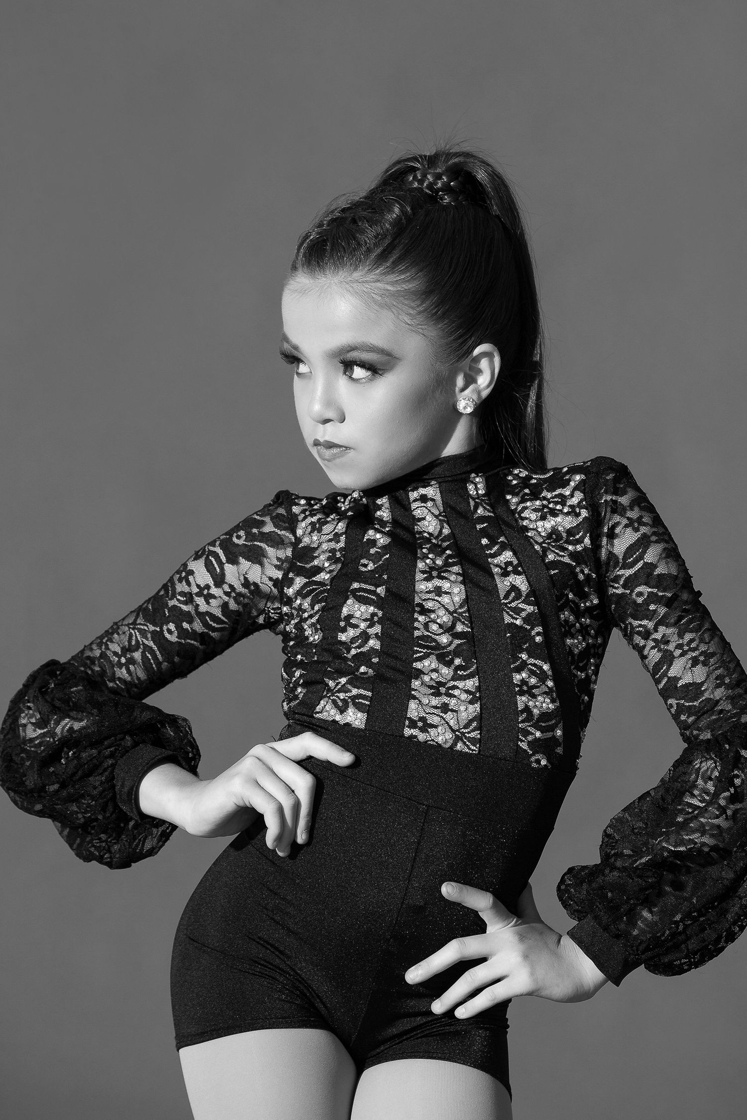 Dramatic black and white portrait of dancer in vintage-style lace bodysuit with long sleeves striking elegant pose.