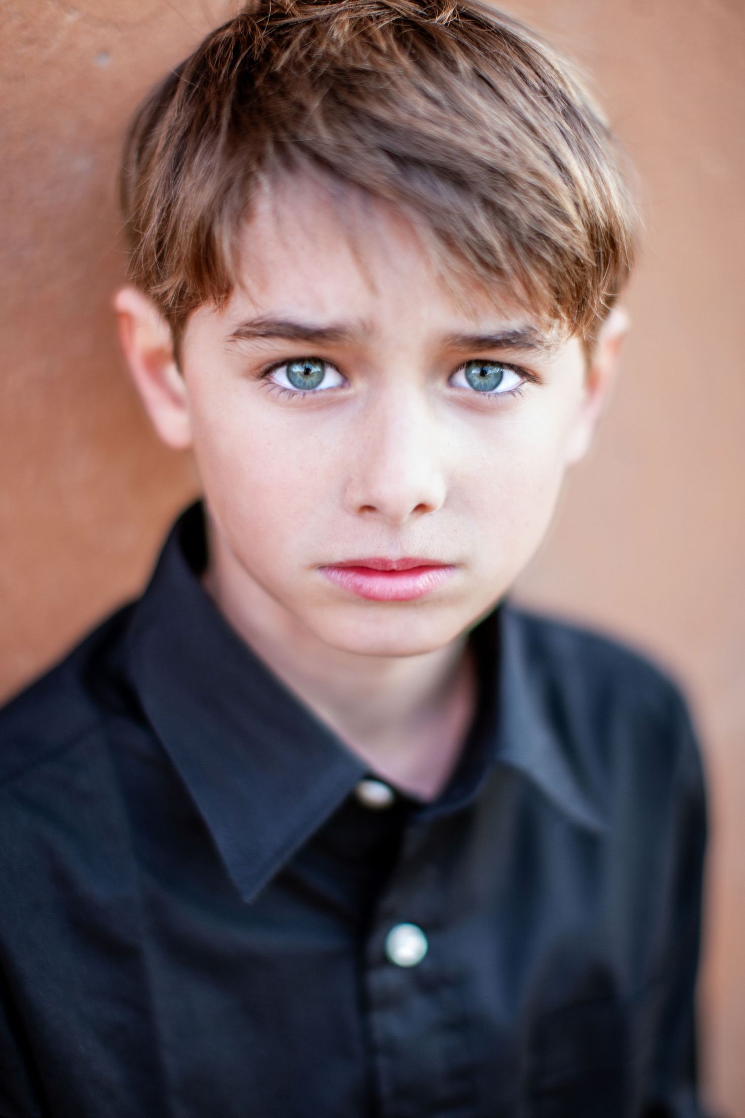 Portrait series against brown background showing facial expressions in black collared shirt with dramatic natural lighting.
